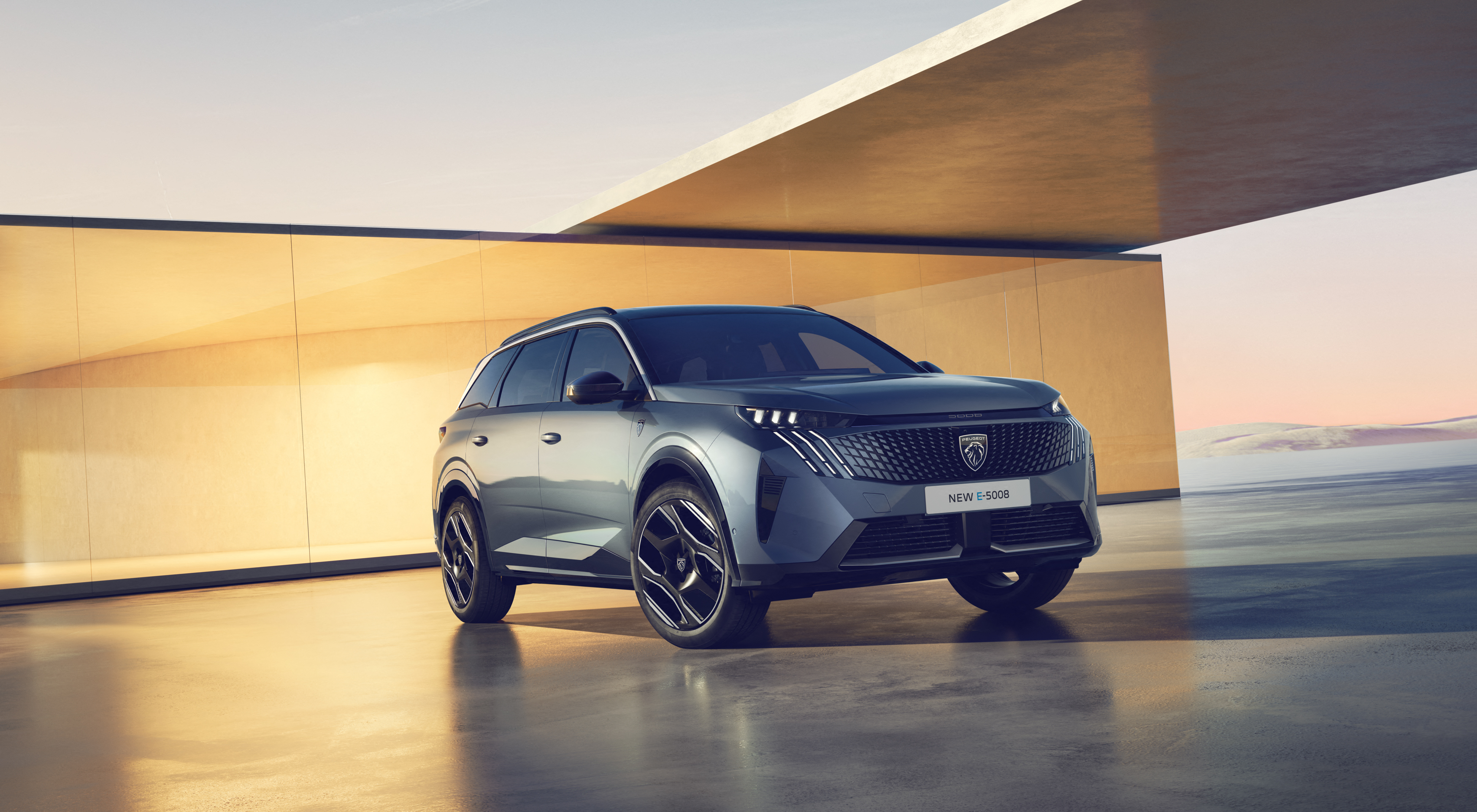 Ein neuer blauer Peugeot vor einem roten Haus